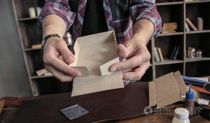 年輕男子皮革制造商手動組裝產品的紙板包裝盒子